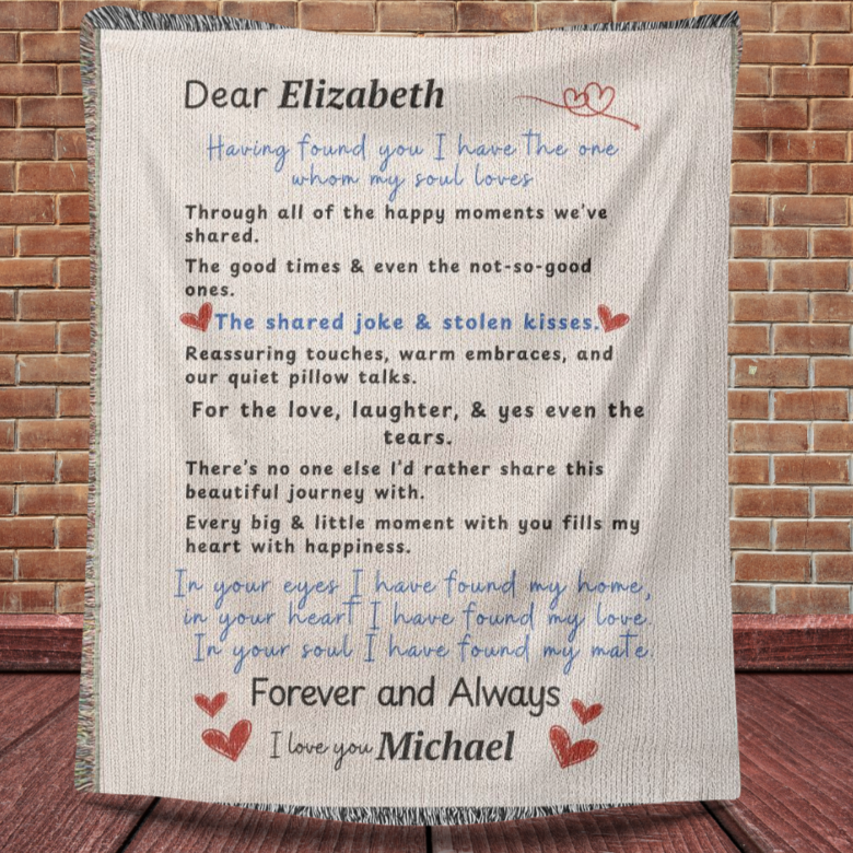 A family heirloom blanket it is a love letter.  A Personalize Gift with custom names. Hanging infront of a brickwall with wooden floors. 