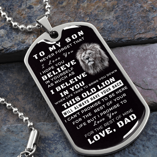 Military dog tag style necklace with a message to a son from father.  Includes a picture of an old lion.  The necklace is laying against a stone background.