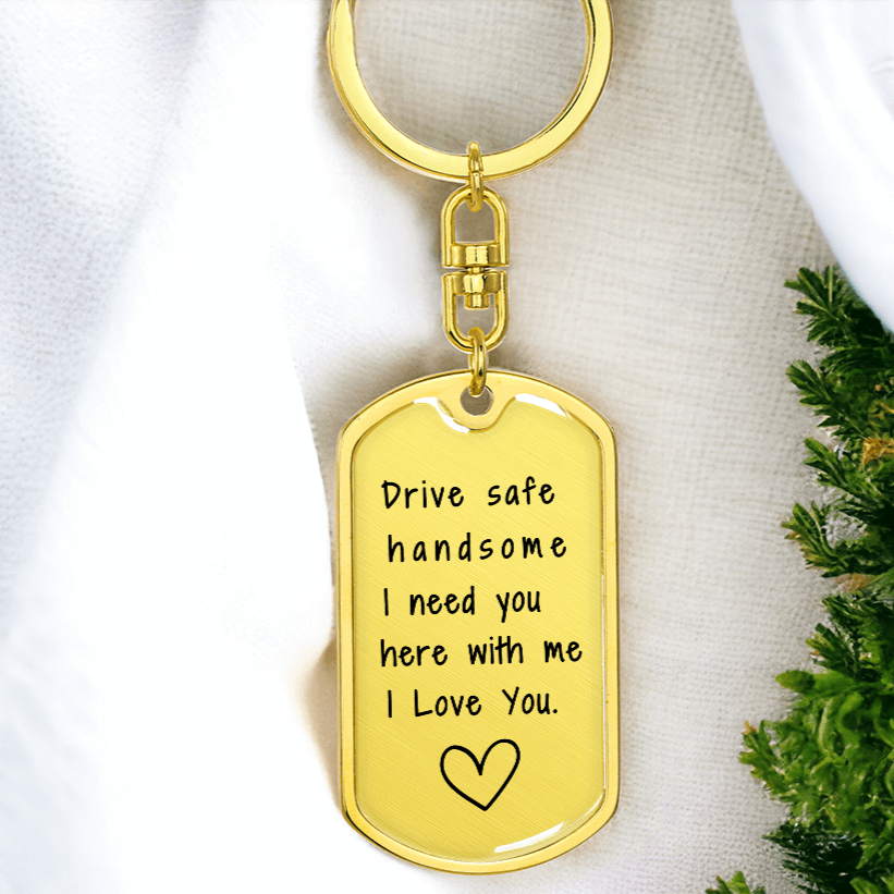 Close-up of gold engraved message on military dog tag keychain, reading 'Drive Safe Handsome, I Need You Here with Me, I Love You' with a heart outline